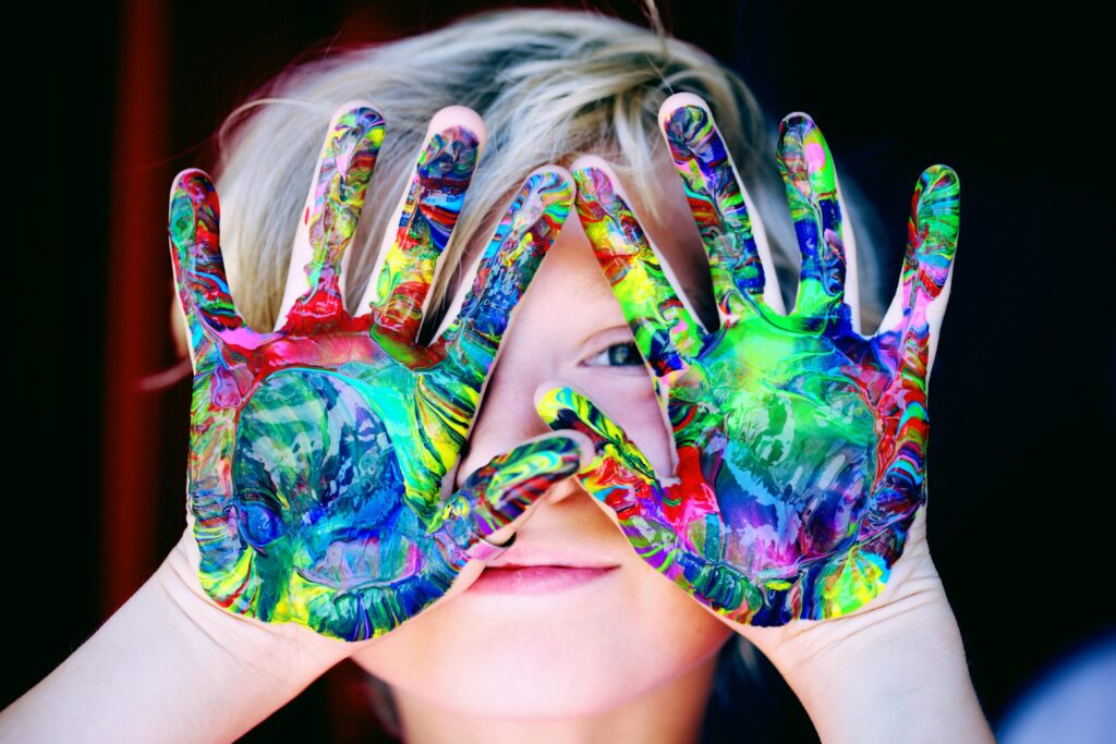 Vibrant close-up of a child's hands covered in colorful paint, expressing creativity and fun.